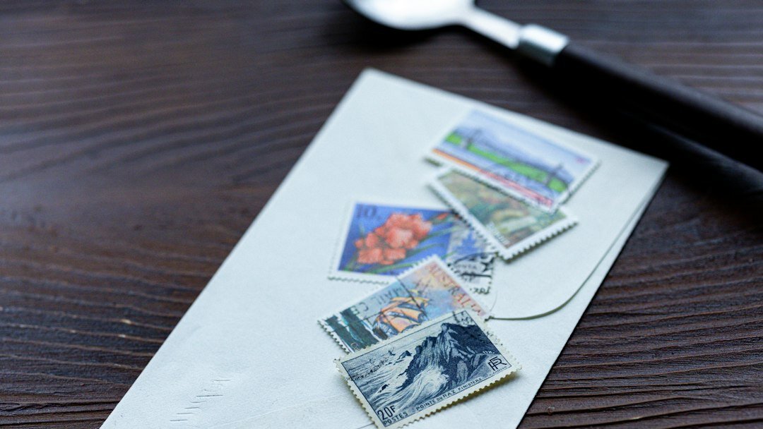 Sellos postales y postales antiguas dispuestas sobre una mesa de madera con una lupa